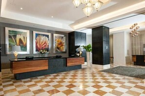 Un vestíbulo de hotel con piso a cuadros, una recepción y obras de arte abstracto en la pared.