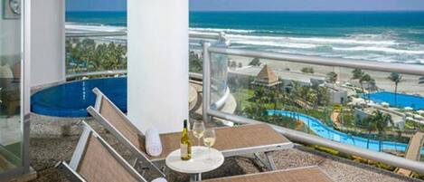 A balcony with a view of the ocean and a resort area.