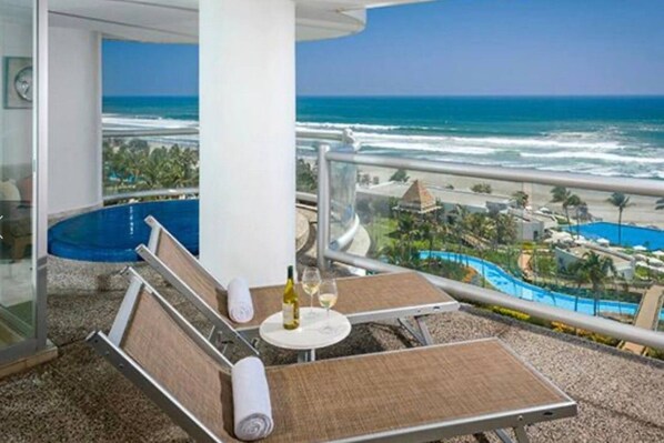 A balcony with a view of the ocean and a resort area.