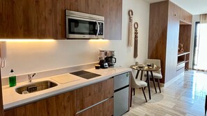 Uma cozinha moderna com armários de madeira, micro-ondas embutido, máquina de café e uma área de jantar com mesa e cadeiras.