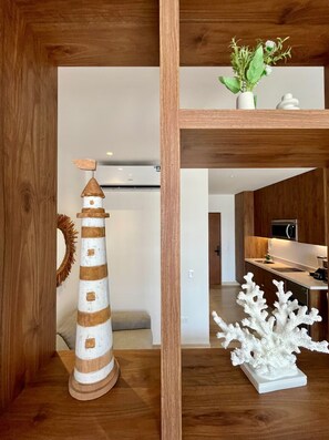 A wooden shelf with a lighthouse model, a white coral sculpture, and a potted plant. - Studio 5th Av, Fast Wi-Fi, Rooftop Pool & Gym (Playa del Carmen)