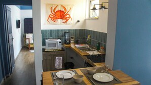 A compact kitchen with a microwave, coffee maker, and a large decorative crab on the wall. - Modern loft in Belém with solar energy - At Doca Umarizal - downtown (Belém)