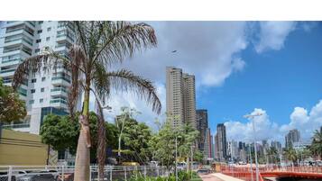 A cityscape with tall buildings, a palm tree, and a red bridge.