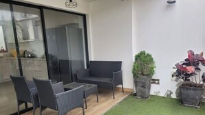 A patio with wicker furniture, a small lawn, and potted plants.