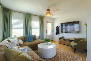 Ein Wohnzimmer mit einer Couch, einem runden Couchtisch, einem Fernseher und einem Deckenventilator.