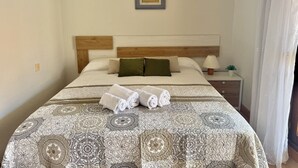 A neatly made bed with rolled towels, a bedside table with a lamp, and a framed picture on the wall. - Las Amapolas Apartment - 12018 (Ajo)