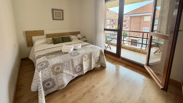 A bedroom with a bed, a chandelier, a large window, and a balcony. - Las Amapolas Apartment - 12018 (Ajo)