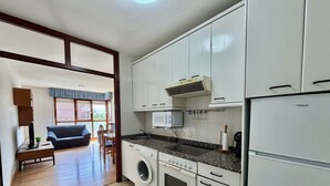 A compact kitchen with a washing machine, microwave, and a refrigerator. - Las Amapolas Apartment - 12018 (Ajo)