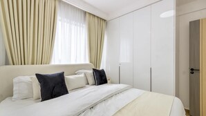 A hotel room with a bed, curtains, a wardrobe, and a door. - 1 Bedroom in Westlands, Nairobi ,parking, WiFi,Gym (Nairobi)