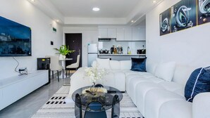 A modern living room with a white sofa, a coffee table, and a dining area with a white table and chairs. - 1 Bedroom in Westlands, Nairobi ,parking, WiFi,Gym (Nairobi)