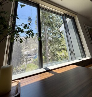 A room with a large window, a wooden table, and a candle. - Amazing Mountain Views Palisades Condo A+ Location (Olympic Valley)