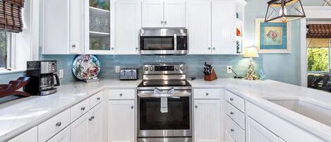 A kitchen with white cabinetry, a stainless steel oven, a microwave, and a toaster.