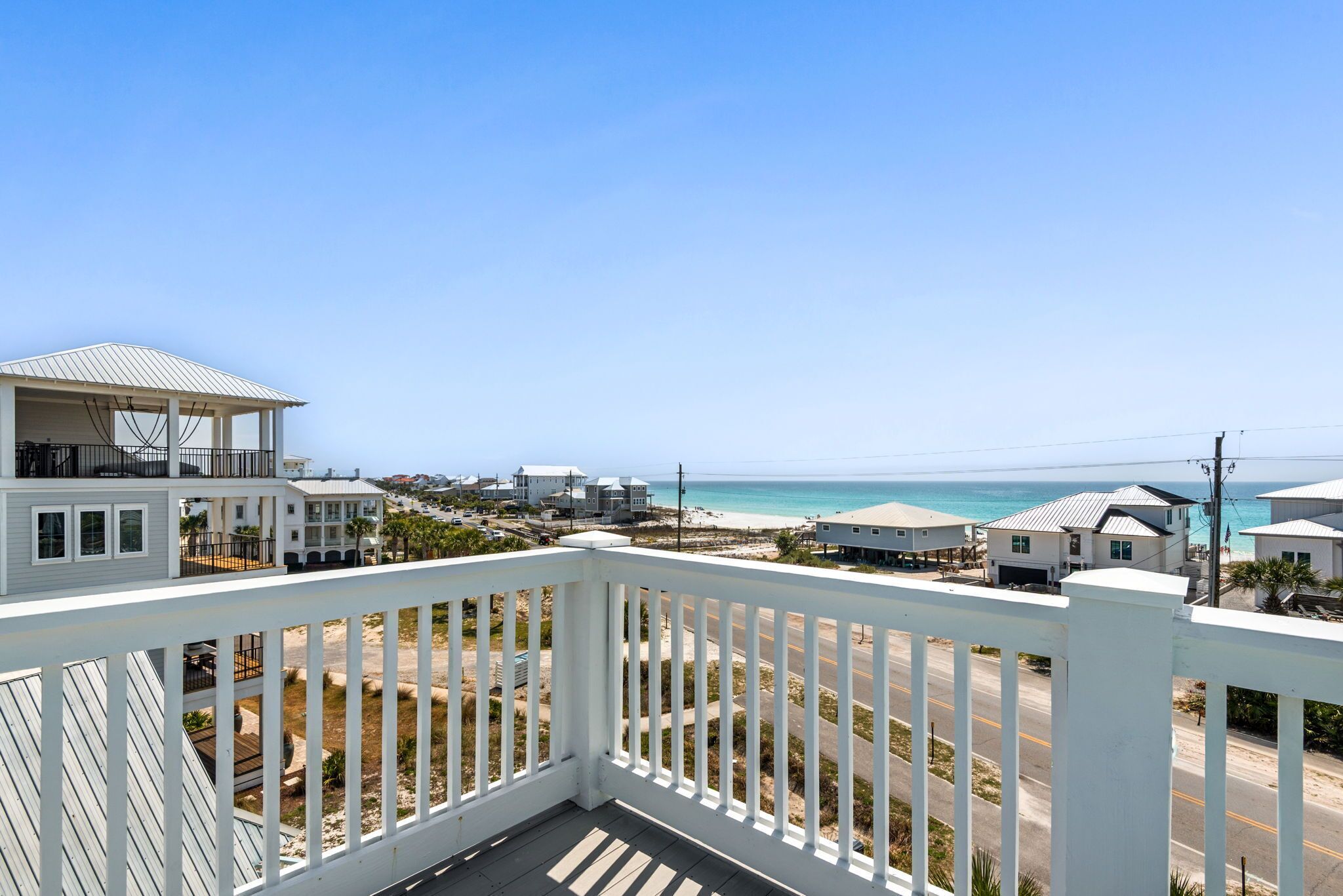 Un quartier résidentiel en bord de mer, avec un immeuble blanc, un balcon et une vue sur la plage et l’océan.