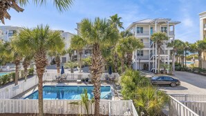 A pool area with palm trees, a car, and a building with balconies. - 5BR Home w/ Pool Table in Seagrove - Steps From the Beach & Pool - Sleeps 12 (Santa Rosa Beach)