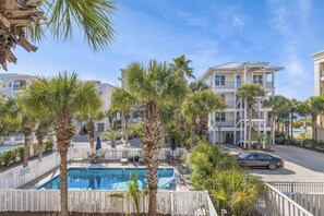 A pool area with palm trees, a car, and a building with balconies. - 5BR Home w/ Pool Table in Seagrove - Steps From the Beach & Pool - Sleeps 12 (Santa Rosa Beach)
