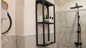 Un baño con un estante negro, una ducha y un revestimiento de mármol en la pared.