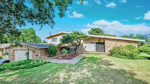 Une maison à deux étages avec un garage, une pelouse bien entretenue et de grands arbres.
