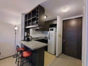 A compact kitchen with a central island, a microwave, and a refrigerator. - Beautiful apartment close to the subway and Barrio Italia, ideal for long stays. (Santiago)