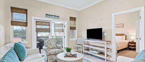 Ein geräumiges Wohnzimmer mit einer Sofagarnitur, einem Fernseher auf einem Holzständer und einem Schild mit der Adresse.