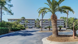 A multi-story hotel with a central courtyard, palm trees, and a clear blue sky.