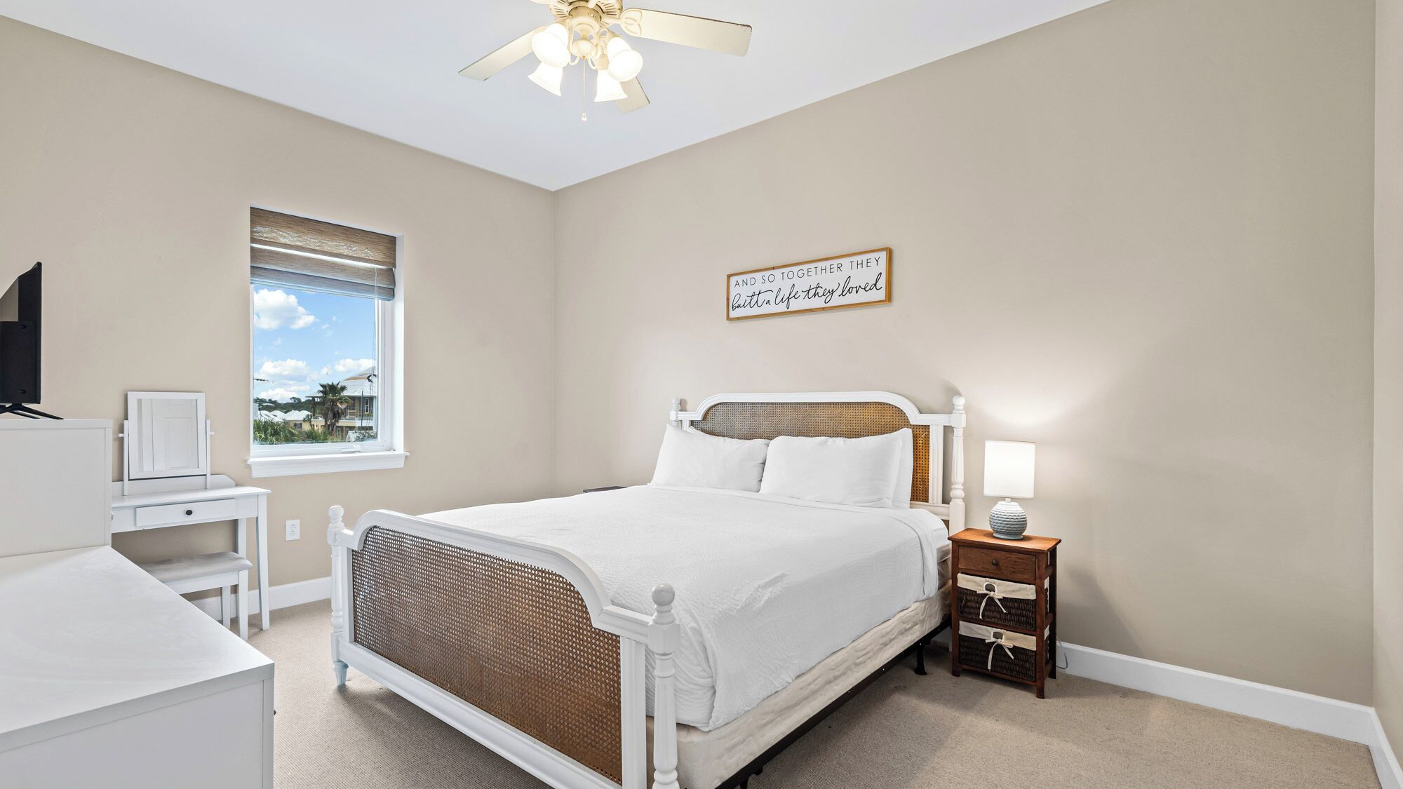 A bedroom with a bed, bedside table, lamp, and a window with blinds.