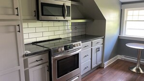 Una cocina equipada con microondas, estufa, horno y armarios blancos.