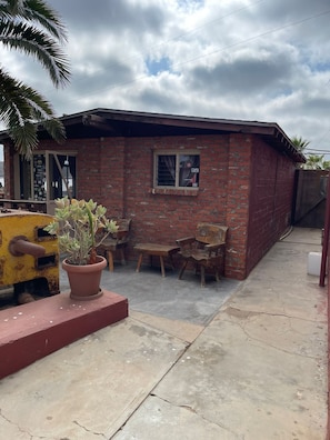 A small brick building with a patio, a potted plant, and a yellow object. - Old Mill Hotel  (San Quintín)