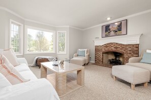 Ein Wohnzimmer mit Kamin, weißen Möbeln und großen Fenstern.