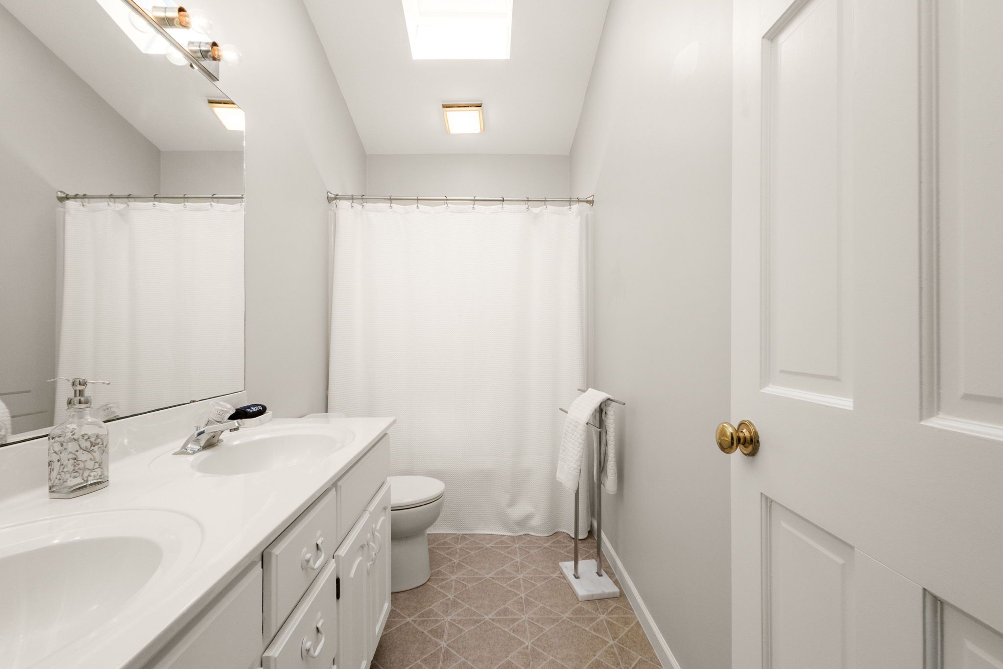 Une salle de bain avec un lavabo blanc, des toilettes et un rideau de douche.