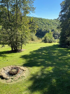 Un campo cubierto de hierba con un hogar a leña y árboles.