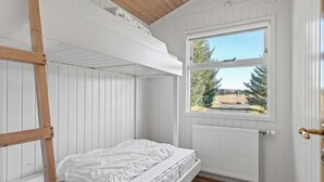 Ett sovrum med en våningssäng, ett fönster med utsikt och ett element.
