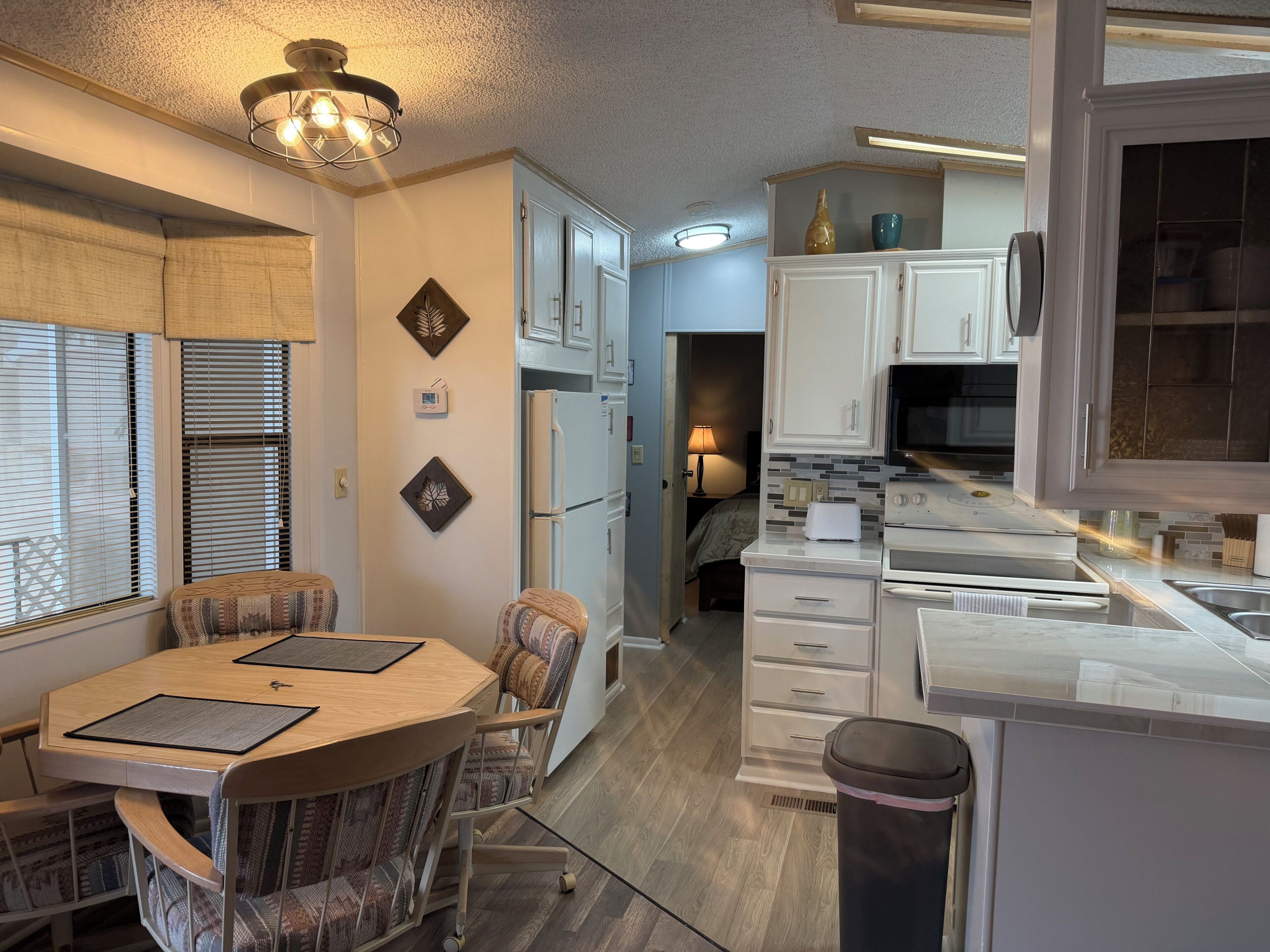 A compact kitchen with a dining area, a refrigerator, a microwave, and a sink.