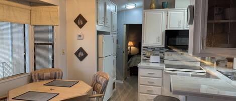 A compact kitchen with a dining area, a refrigerator, a microwave, and a sink.