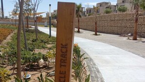 A wooden sign with 'BICYCLE TRACK' engraved, surrounded by plants and a paved path. - Spacious 3-bedroom apartment in tranquil Cairo with AC (Cairo Governorate)