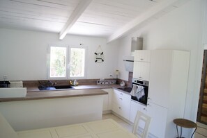 A kitchen with white cabinets, a wooden countertop, a sink, and a stove. - Charming house in a green setting, between scrubland and sea (Zonza)