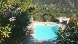 A swimming pool surrounded by lush greenery and a view of a hilly landscape. - Charming house in a green setting, between scrubland and sea (Zonza)