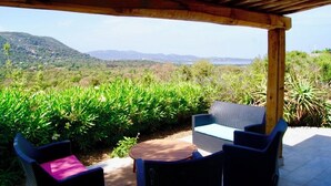 An outdoor patio with wicker furniture and a view of a mountainous landscape. - Charming house in a green setting, between scrubland and sea (Zonza)