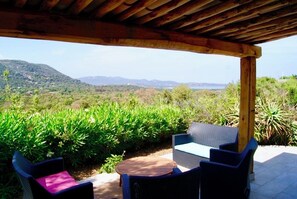 An outdoor patio with wicker furniture and a view of a mountainous landscape. - Charming house in a green setting, between scrubland and sea (Zonza)