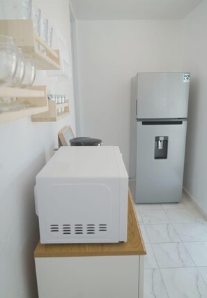 A compact kitchen with a white refrigerator, a microwave, and a wooden countertop. - Apt para 2 / WiFi + Parking / 10 min aeropuerto (Carolina)