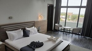 Una habitación de hotel con una cama grande, mesitas de noche, un escritorio y vistas a la ciudad.