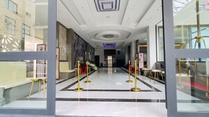 Un vestíbulo de hotel con suelo de mármol, cuerdas de terciopelo rojo y barandillas doradas.