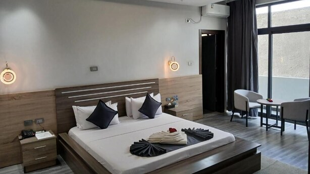 Una habitación de hotel moderna con una cama grande, mesitas de noche, un escritorio y una silla.