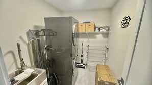 Een kleine keuken met een koelkast, spoelbak en een rek om het servies te drogen.
