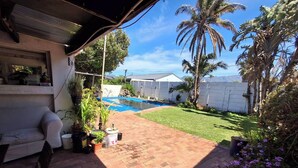 A backyard with a swimming pool, a brick patio, and various plants. - Adventure Cape Town 1 (Cape Town)