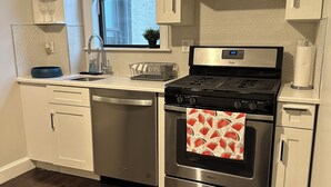 A modern kitchen with stainless steel appliances, a window with blinds, and a wooden floor. - Exc Location & Comfortable Apt 2BD 1BA Downtown JC 12 min to NYC (Jersey City)