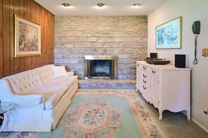 Une pièce avec une cheminée, un canapé blanc, une commode blanche et un mur en pierre.
