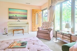 Une pièce avec un piano, une chaise, une table et un tableau accroché au mur.