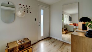 A room with a wooden floor, a white door, a mirror, and a small table with a lamp. - Vista Ashby: Stagecoach Oasis, Pool & Mtn Views (Palm Springs)