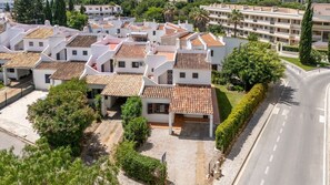 Un quartier résidentiel composé de plusieurs bâtiments blancs, dotés de toits en tuiles de terre cuite, et traversé par une route pavée.