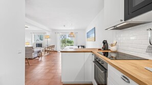 Une cuisine moderne avec des armoires blanches, un plan de travail en bois et un four encastré.